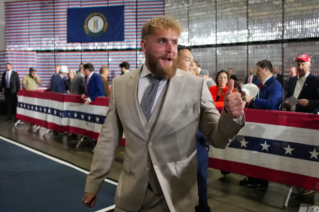 Jake Paul gives a thumbs up while walking past spectators, a Kentucky state flag, and a banner.