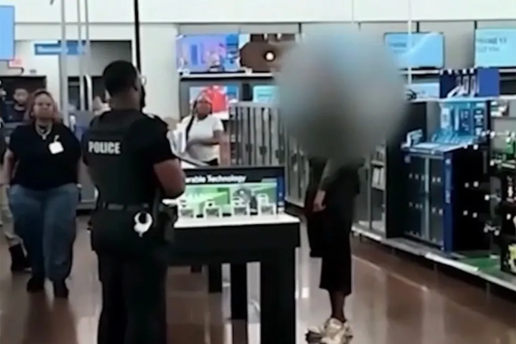 A police officer in a dark uniform stands with their back to the camera inside a store, with customers and merchandise visible around them.