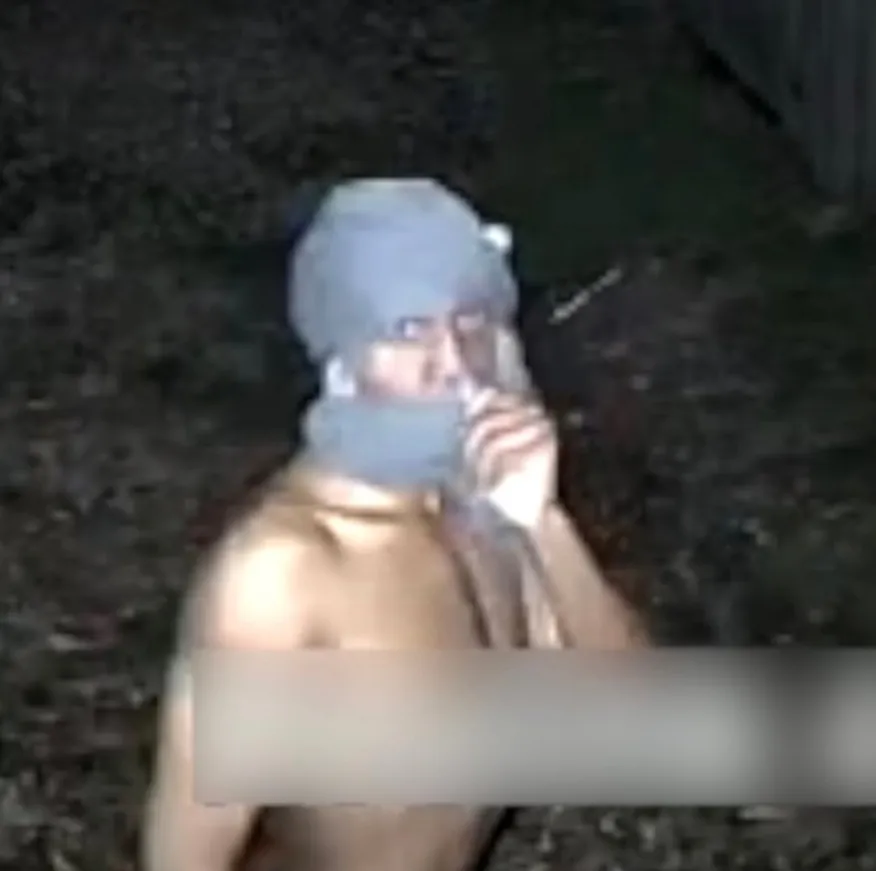 A shirtless person in a beanie and neck warmer, possibly holding a cigarette.