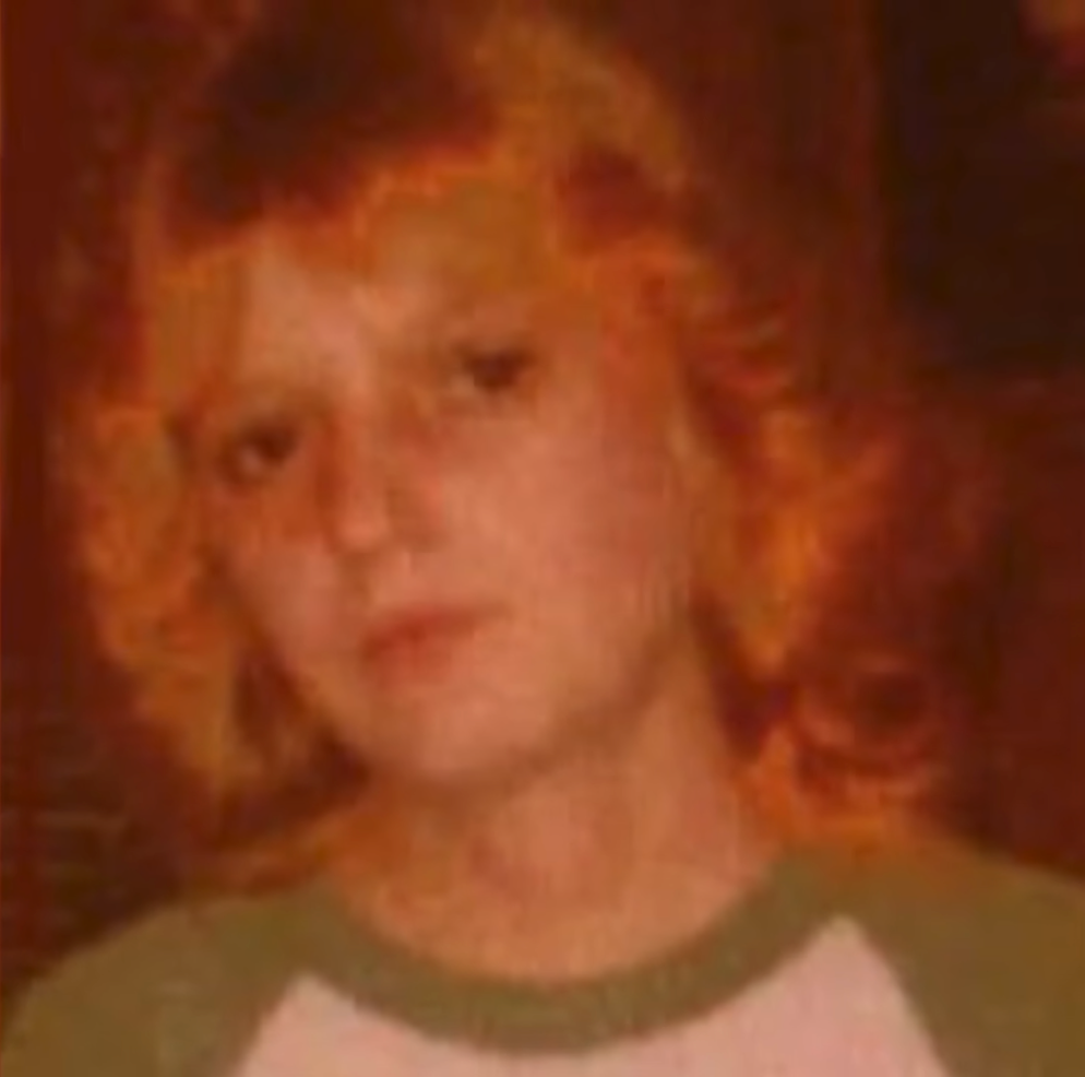 Headshot of Roxanne Sharp with red hair and a green and white shirt.