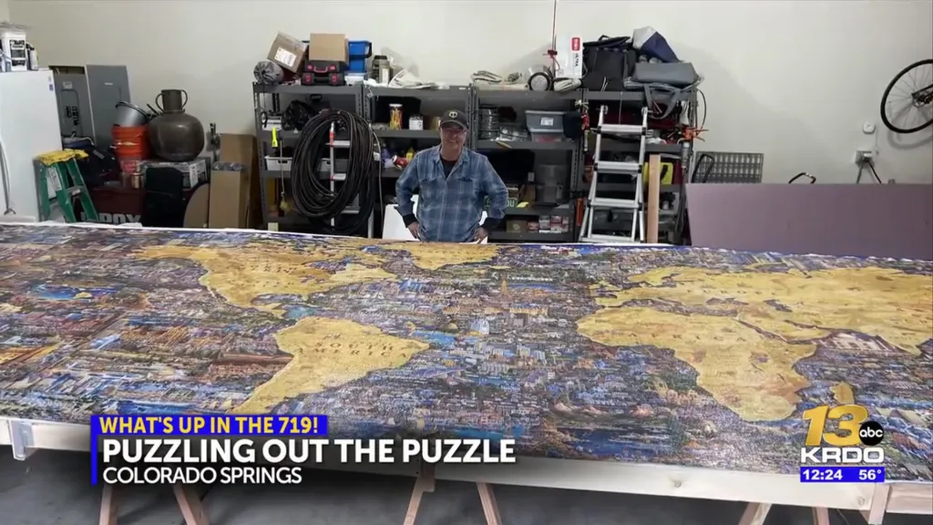 A man standing behind a massive, completed world map puzzle.