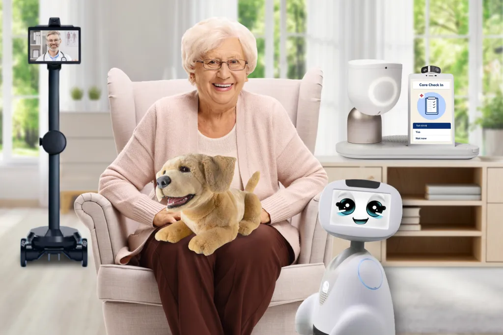 A senior woman with a robotic dog on her lap is surrounded by a telemedicine screen on a stand, a care-check-in robot, and a companion robot.
