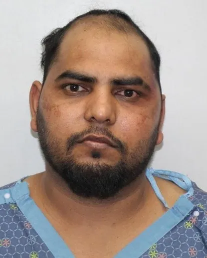 Mugshot of Tarsem Singh with a serious expression and signs of bruising under his eyes.