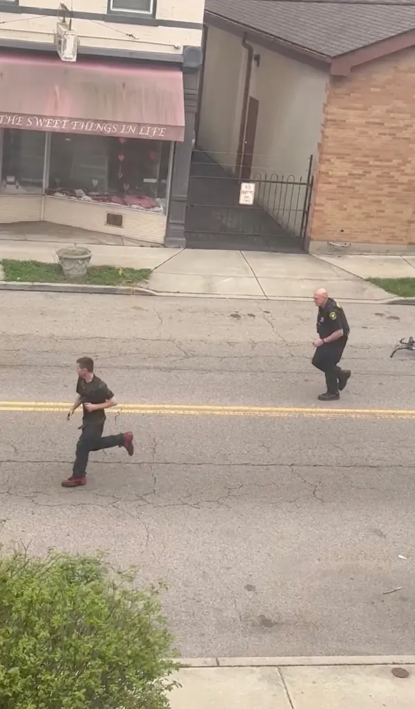 A police officer and a man running in the street.