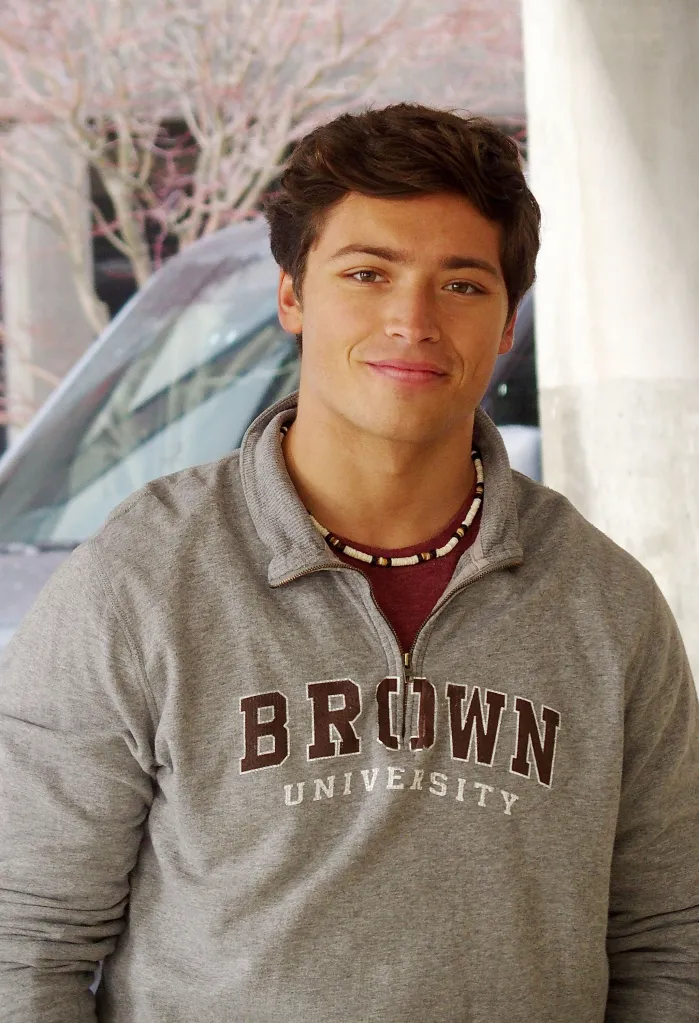 Joaquin Consuelos smiles wearing a grey Brown University sweatshirt.