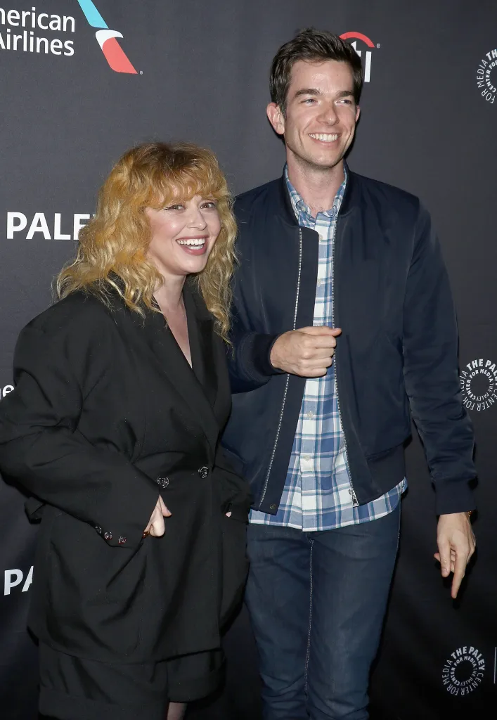 Natasha Lyonne, in a black jacket, and John Mulaney, in a blue jacket and blue and white checked shirt, smile at the 2018 PaleyFest NY event.