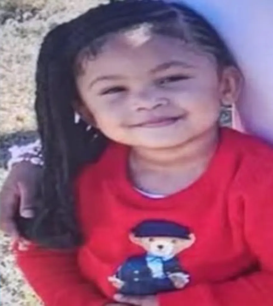 Adrienne Reid, a young girl with braided hair and a red sweater, smiling.