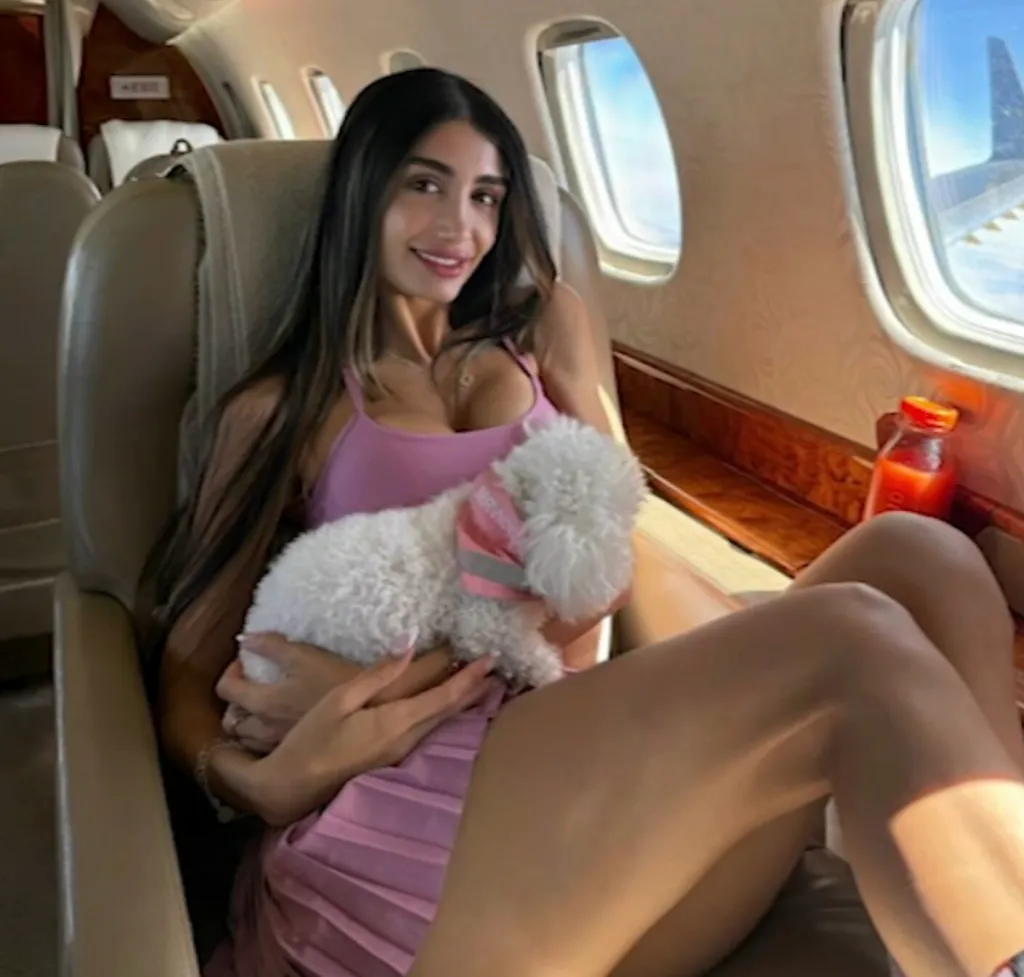 Adva Lavie, an OnlyFans model, holding a small dog while seated on a private jet.
