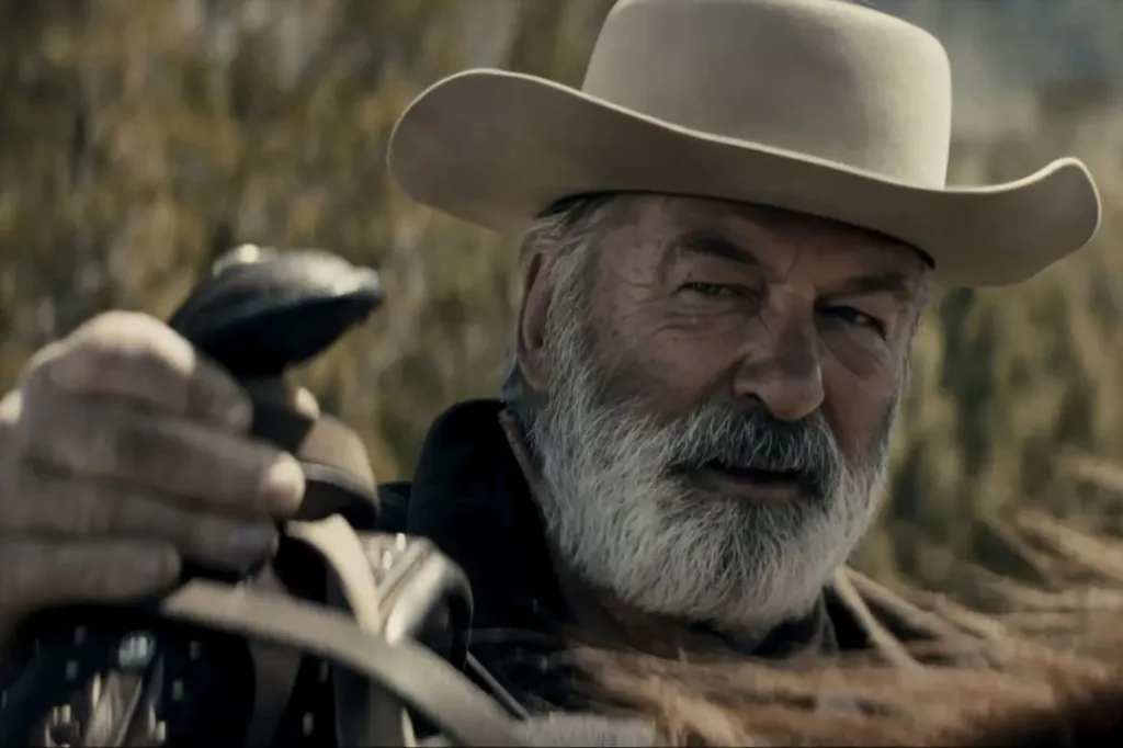 Alec Baldwin as Harland Rust in a cowboy hat and white beard.