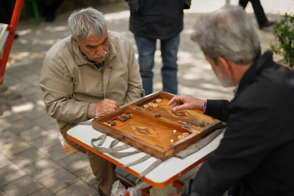 Ali Asghar Nasrulahi playing backgammon with a friend in a public park.