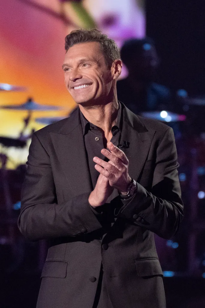 Ryan Seacrest smiling and clapping.