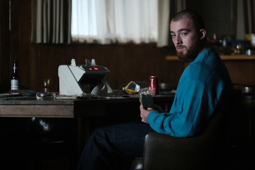 Angus Cloud as Fezco from Euphoria sitting at a table with money.