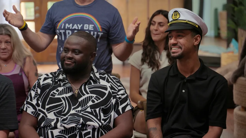 PJ and Anthony, dressed in a black-and-white shirt and a captain's hat, respectively, sit in the foreground.