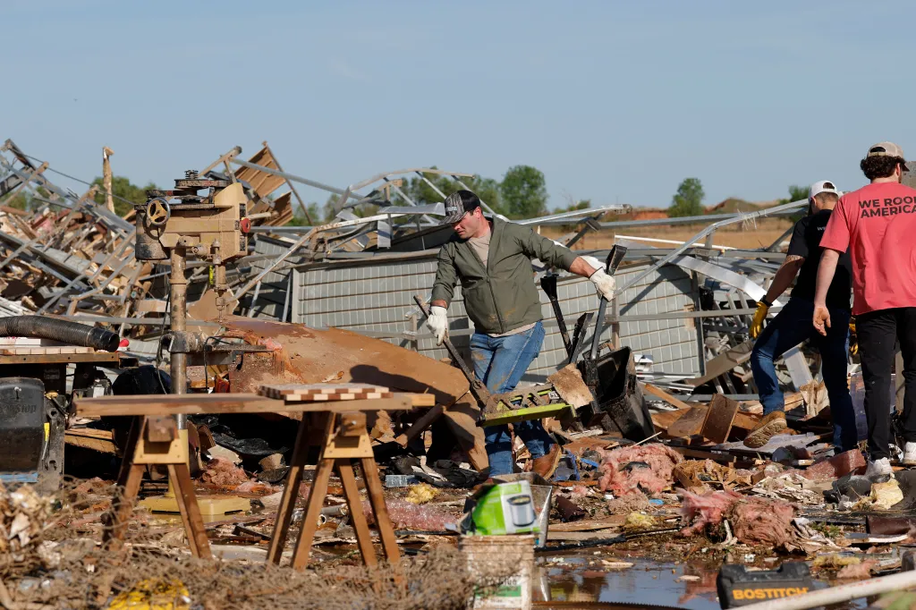 A man clears debris from a commercial woodworking shop after a tornado.