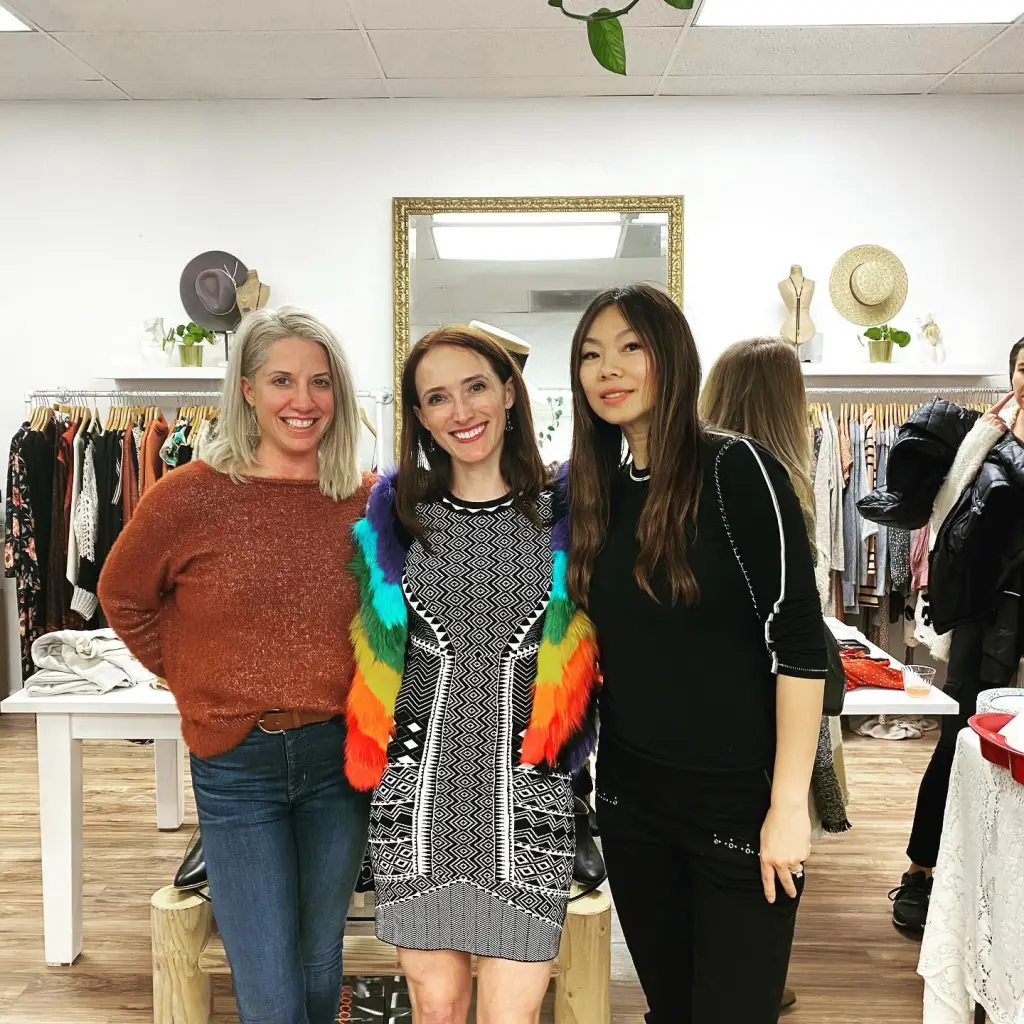 Three women, including Arianna Dillman in the center, pose for a photo in a clothing store.