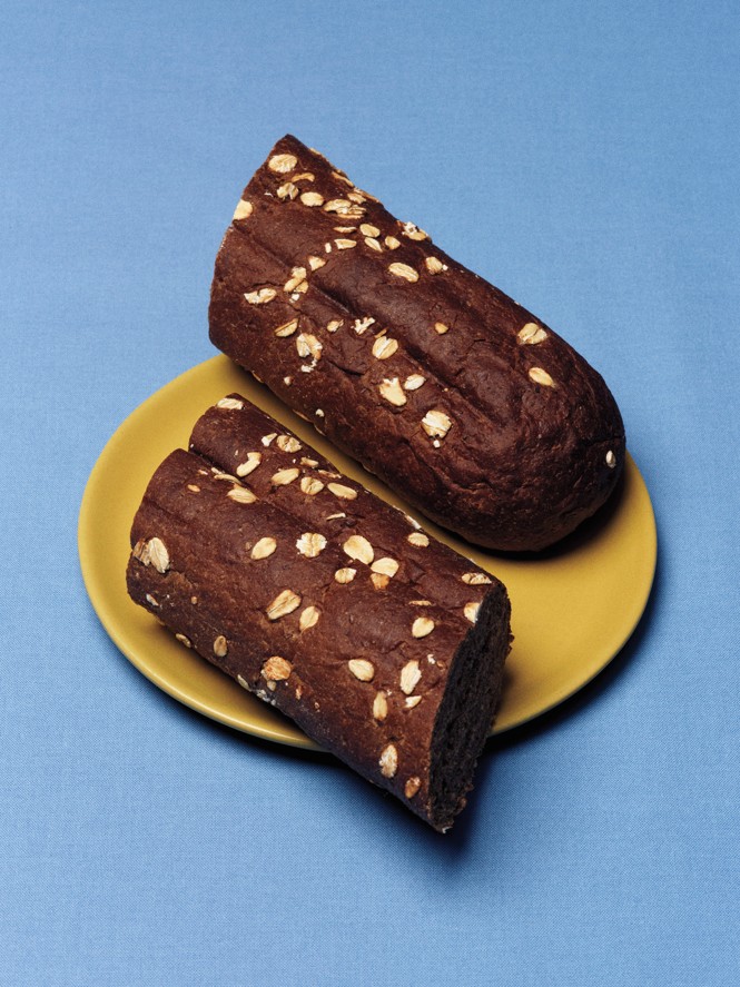 photo of 2 long slices of brown baguette with oats sprinkled on top, on yellow plate with blue background
