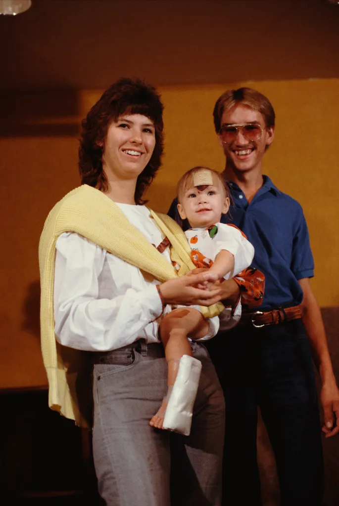 Jessica McClure held by her mother Reba, with father Chip standing next to them.