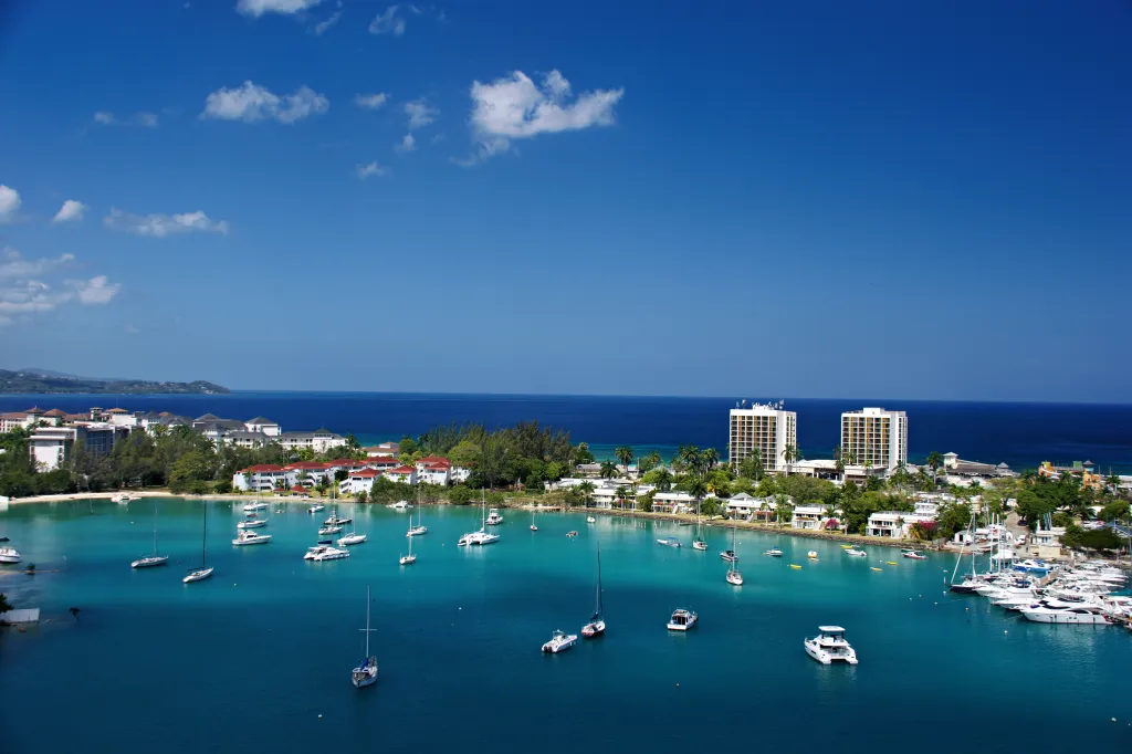 Aerial view of Montego Bay, Jamaica, with boats in turquoise water and buildings along the shore.