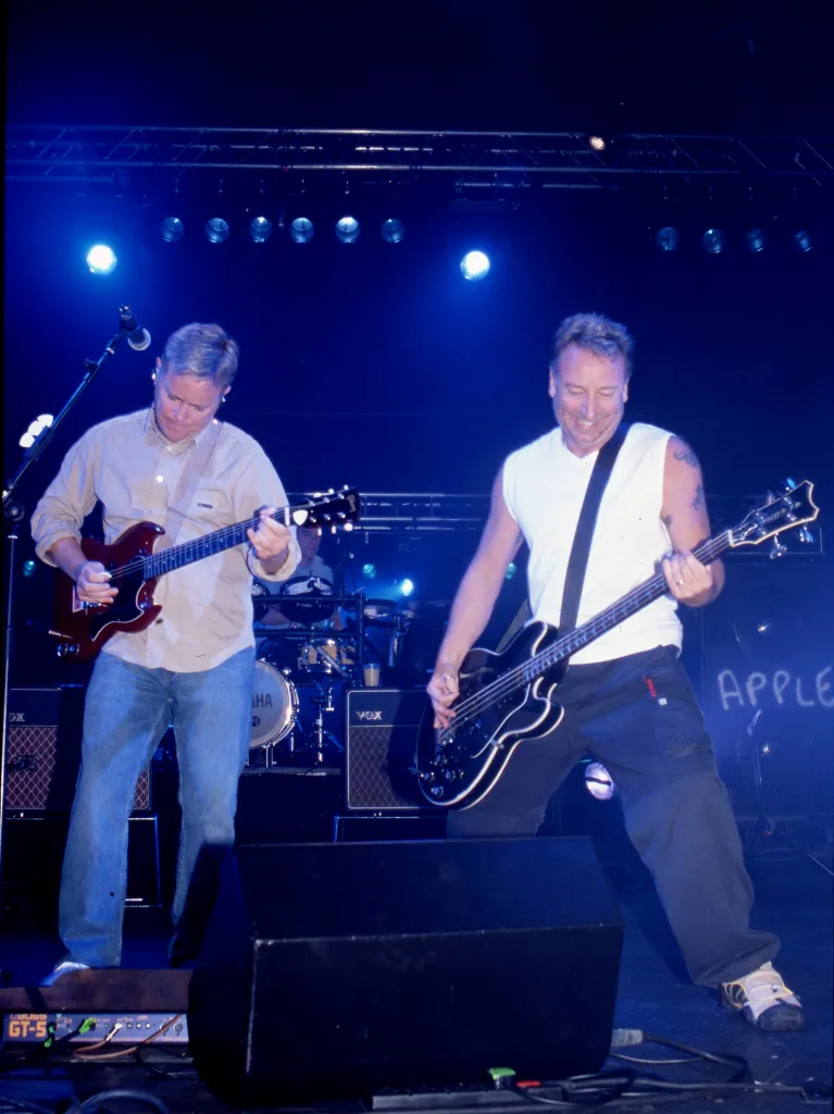 Bernard Sumner and Peter Hook of New Order performing on stage.