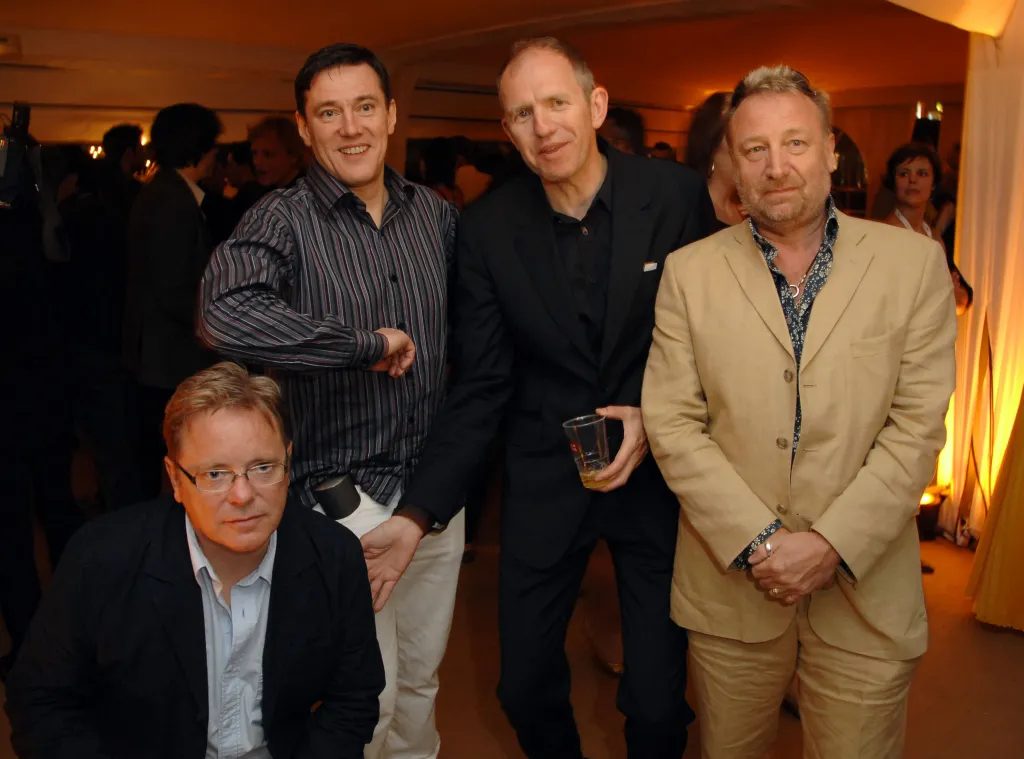 Bernard Sumner, Stephen Morris, Anton Corbijn, and Peter Hook pose for a photo.