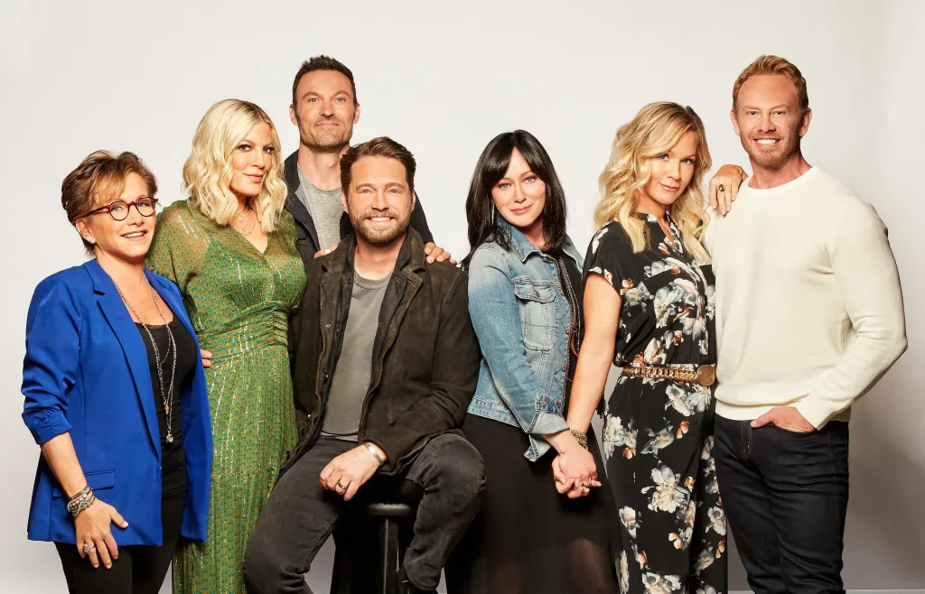 A group photo of the cast of BH90210: Gabrielle Carteris, Tori Spelling, Brian Austin Green, Jason Priestley, Shannen Doherty, Jennie Garth and Ian Ziering.