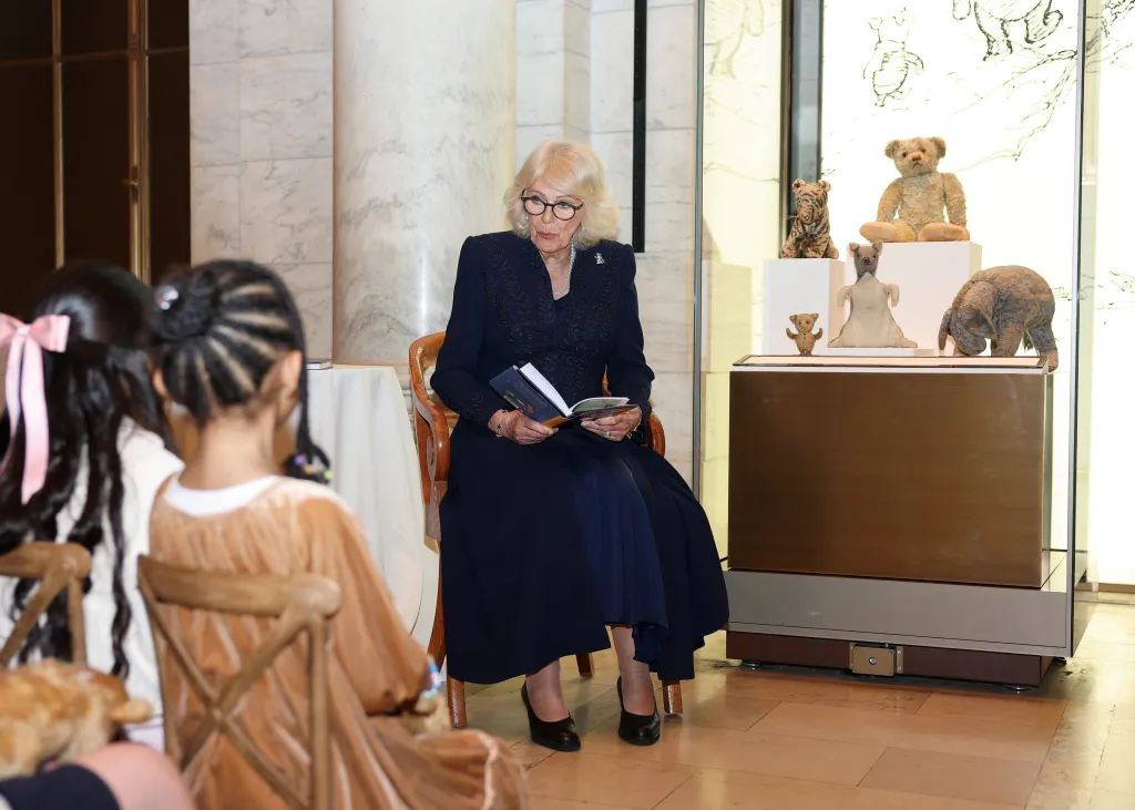 Britain's Queen Camilla, in a navy blue dress, reading Winnie-the-Pooh to children during a literacy event at the New York Public Library.