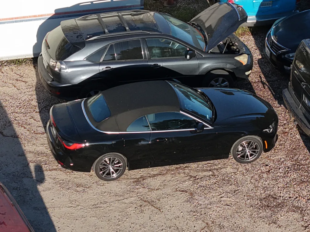 Britney Spears' black convertible car and a grey SUV with its hood up in a tow yard.