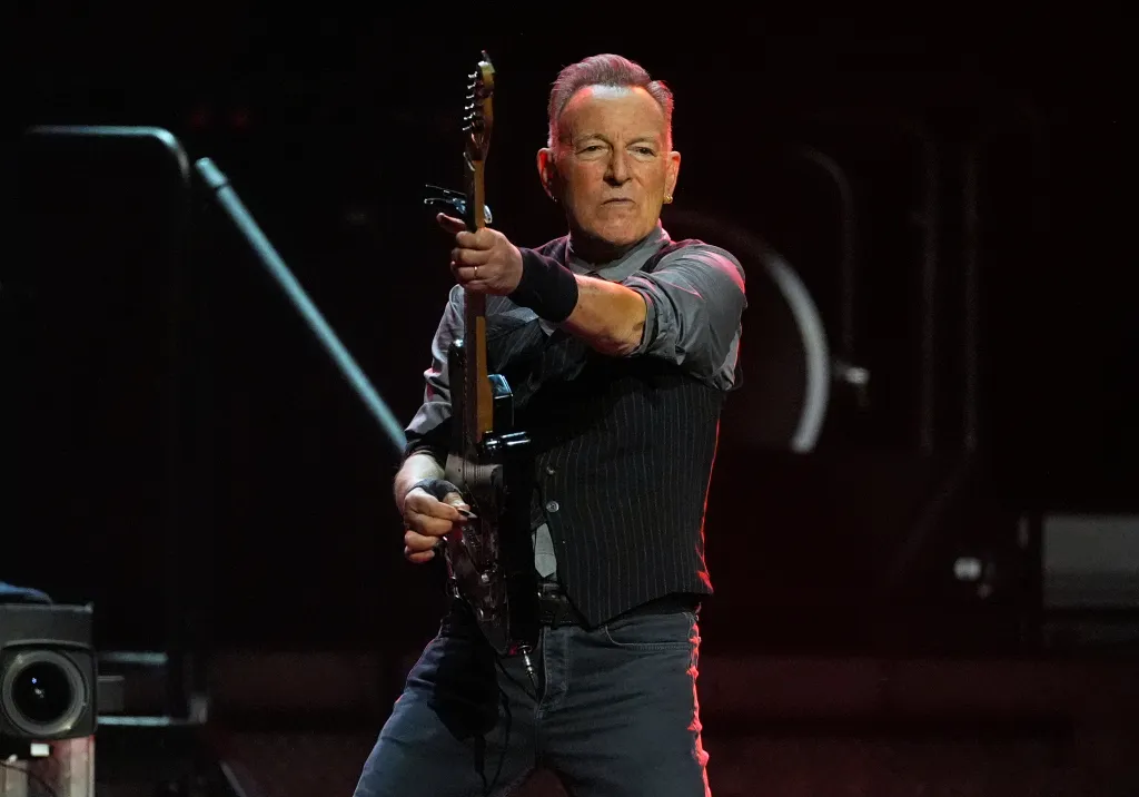 Bruce Springsteen performing on stage with a guitar.