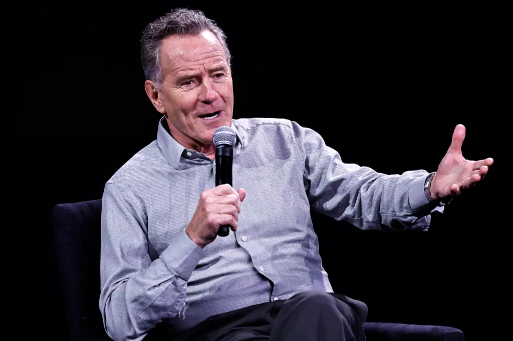 Bryan Cranston speaking into a microphone and gesturing with his hand at the Tribeca Festival.