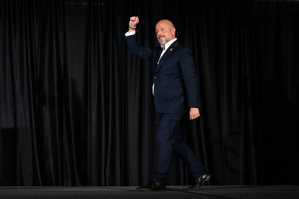 California gubernatorial candidate Steve Hilton walking toward a podium, raising his right fist.