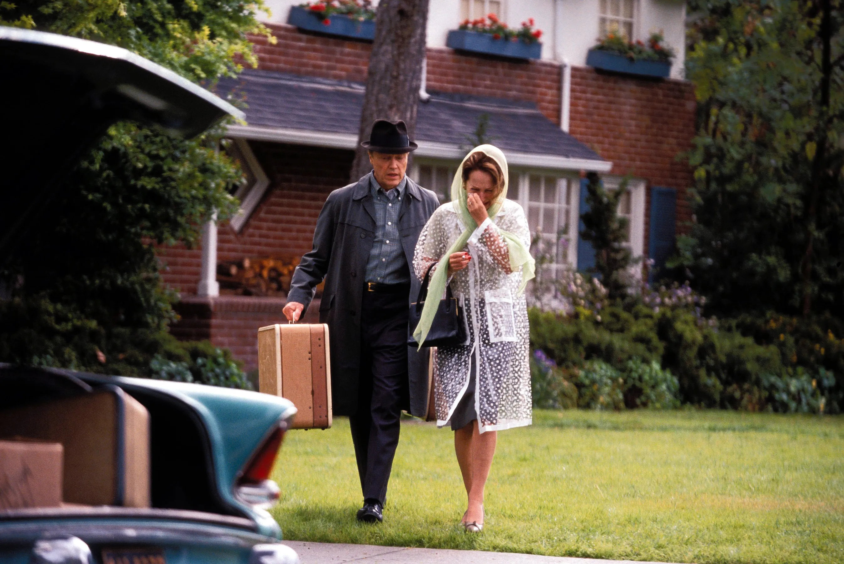 Christopher Walken and Nathalie Baye carry luggage from their house to a car in the film 