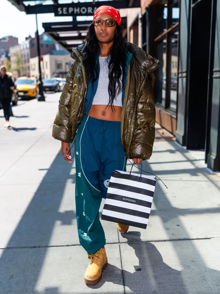 Ciara Miller walking with a Sephora bag on a city street.