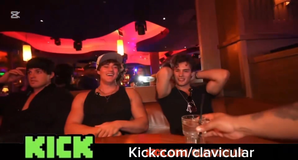 Three men at a bar or club, one reaching for a drink.