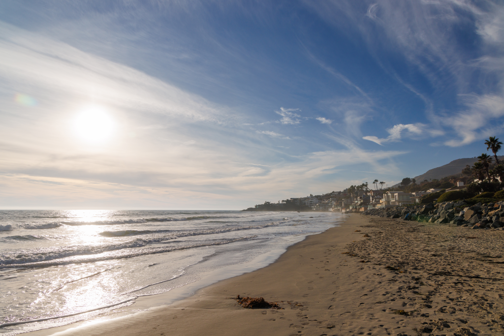Ocean coast in Malibu, California with residential buildings along the shore.