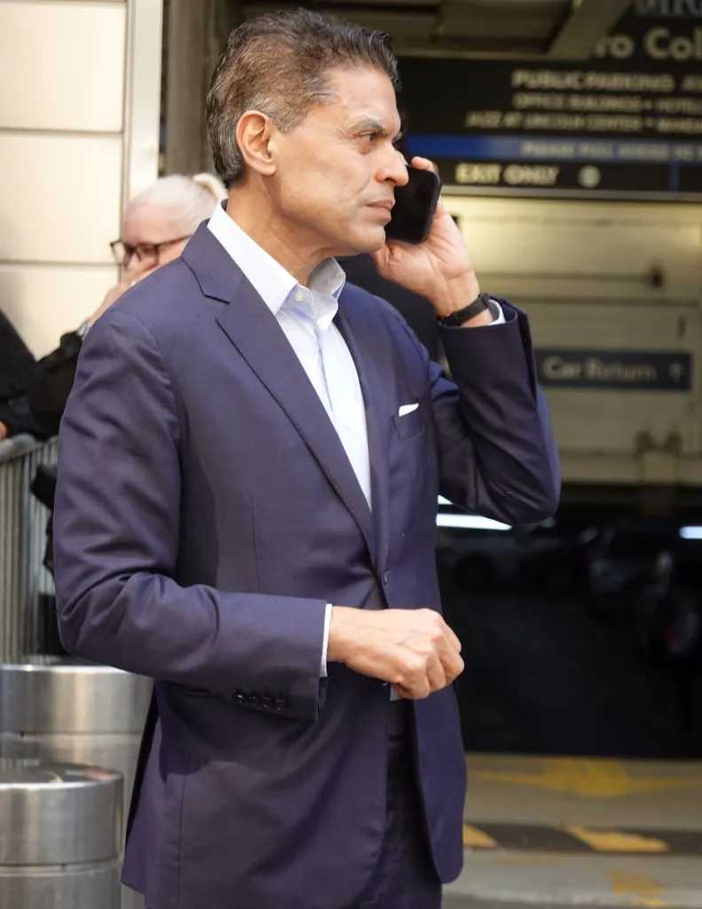 Fareed Zakaria on the phone in a navy blue suit and dress shirt near Columbus Circle.