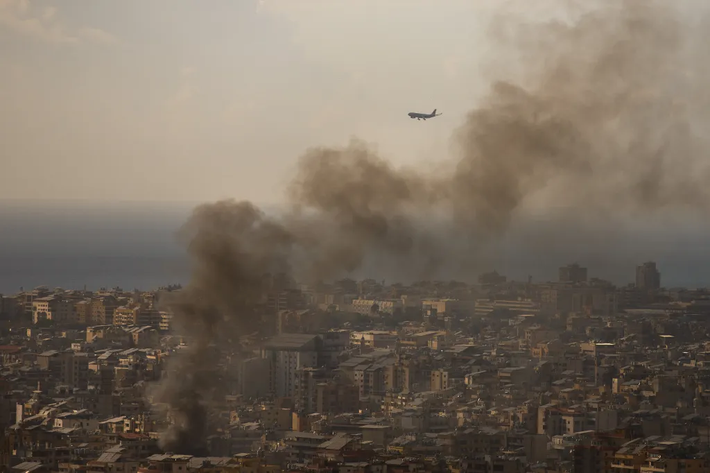 A commercial plane is preparing to land at Beirut Airport as smoke rises from Israeli airstrikes in Dahiyeh, a southern suburb of Beirut, Lebanon, Sunday, April 5, 2026.