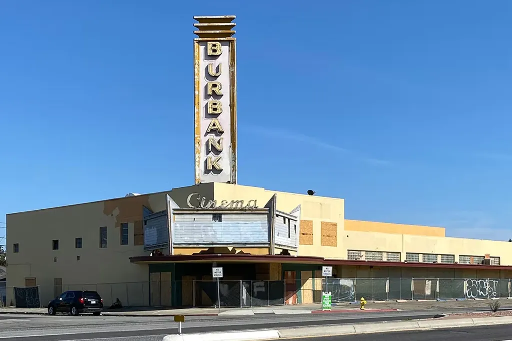 The abandoned Burbank Cinema building with its marquee boarded up and a tall, faded 