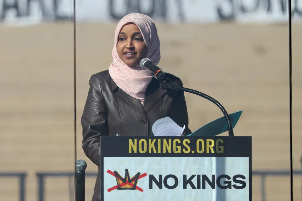 Congresswoman Ilhan Omar speaks at a rally podium with a microphone.