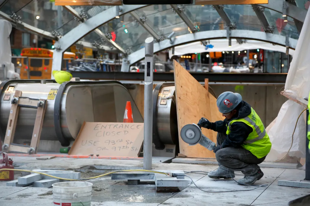 A construction worker cuts stone near an entrance of the unfinished Second Avenue subway.