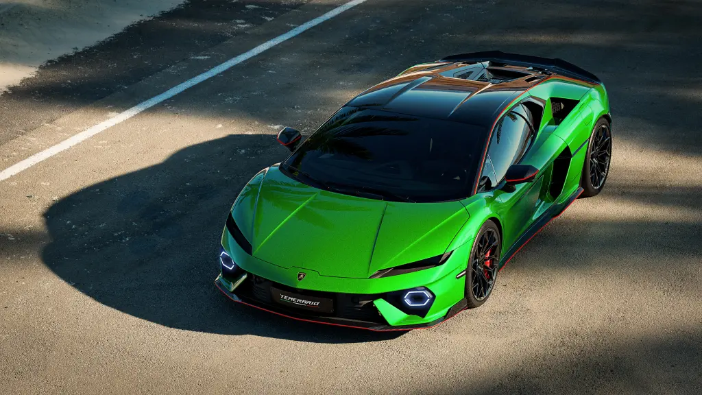 A green Lamborghini on asphalt with its headlights on.