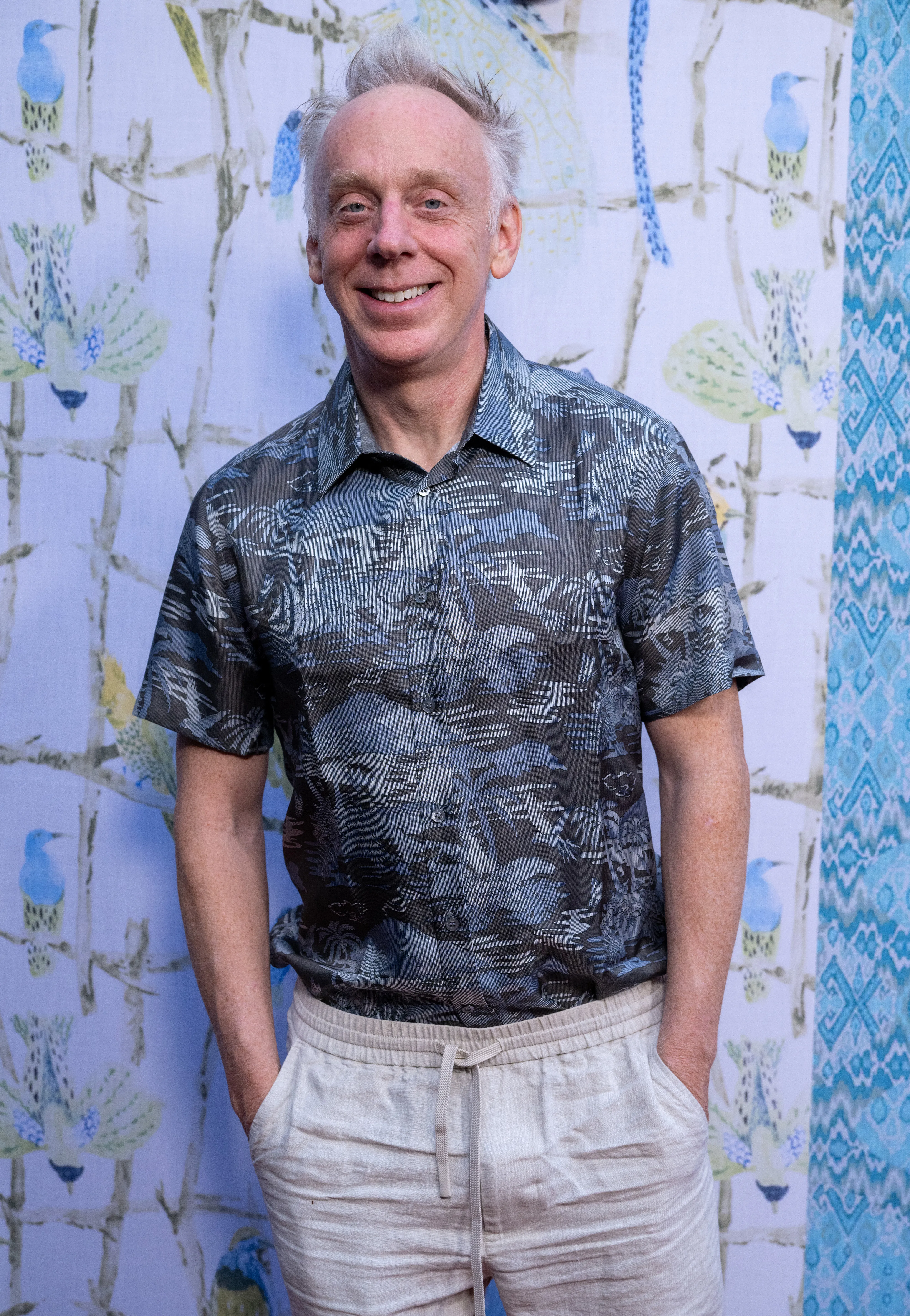 Creator and director Mike White smiles wearing a Hawaiian shirt and drawstring shorts.
