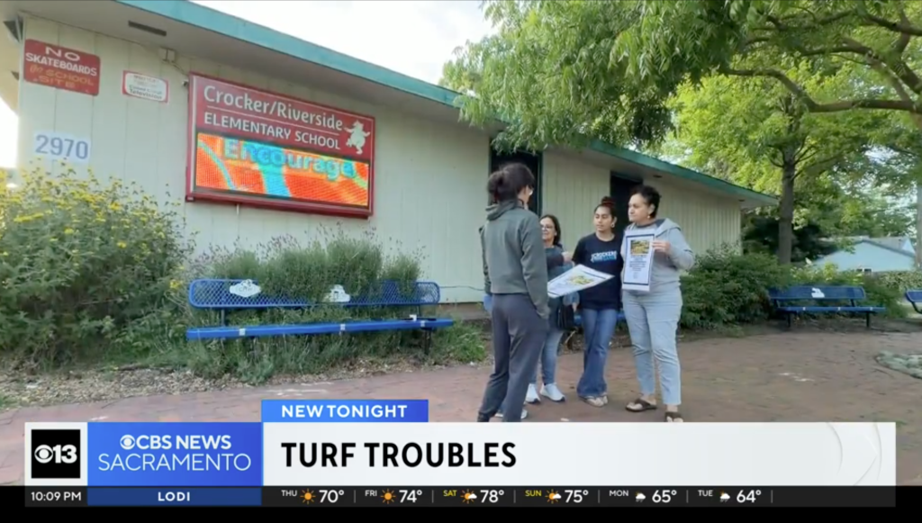 Four parents holding papers, protesting artificial turf at Crocker/Riverside Elementary School.
