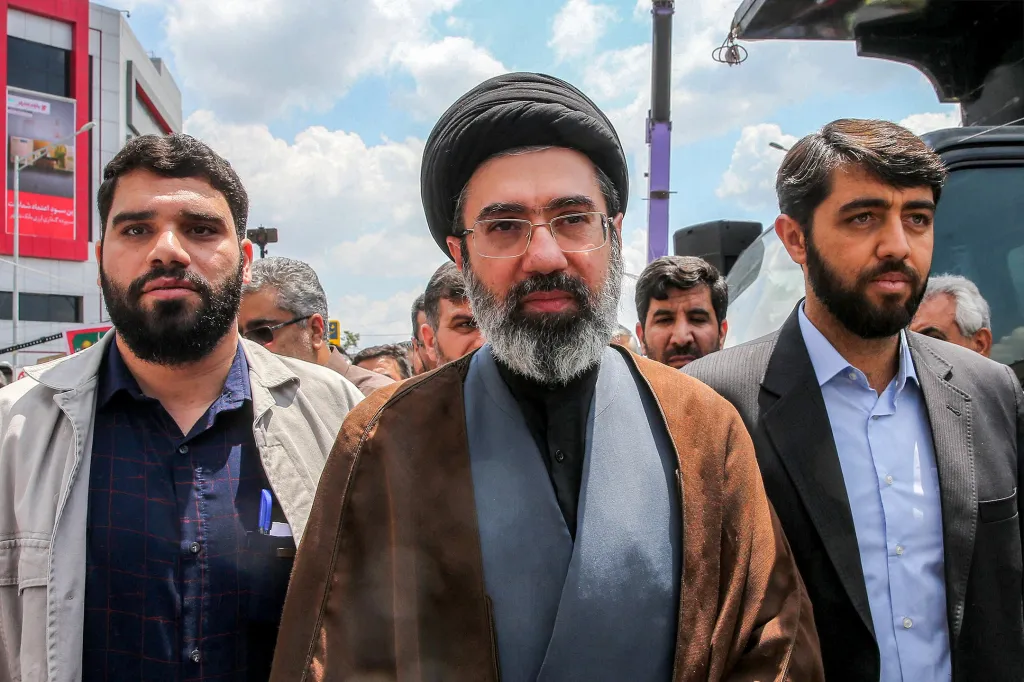 Mojtaba Khamenei walking down a street in Tehran with a crowd of people around him.