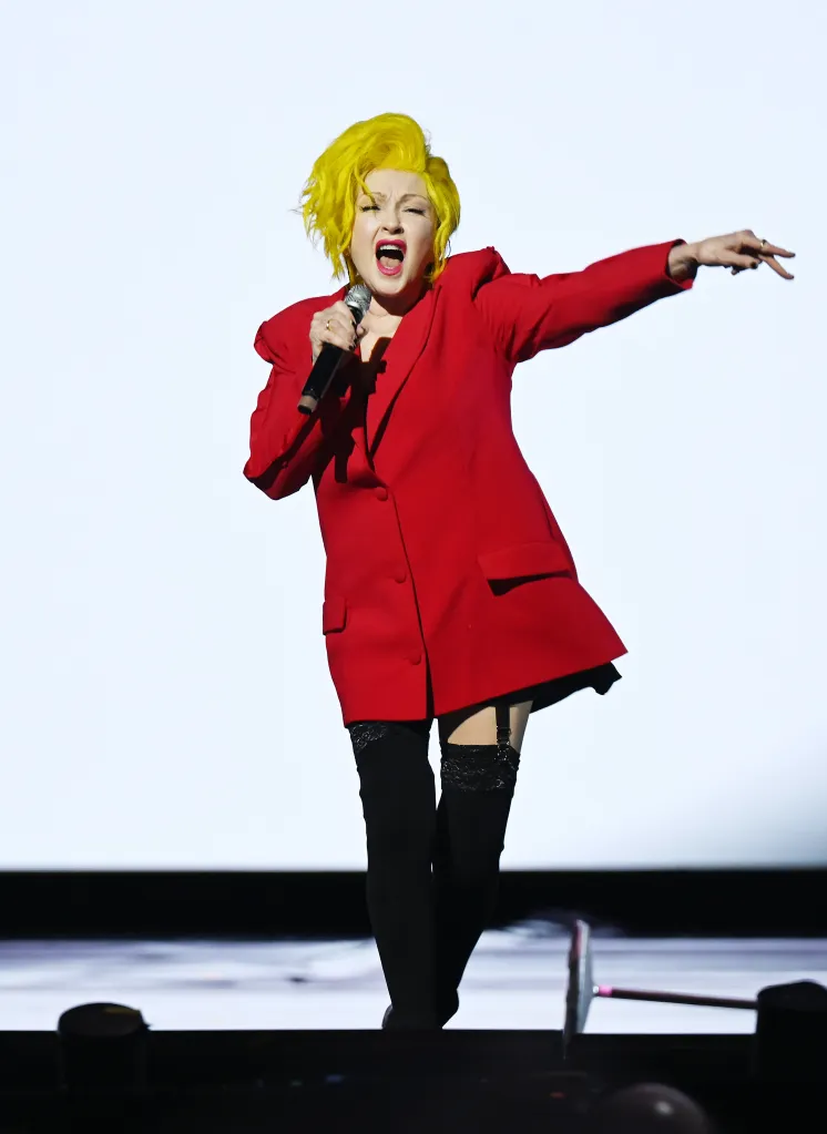 Cyndi Lauper performing at her Las Vegas Residency, wearing a red blazer and thigh-high stockings.