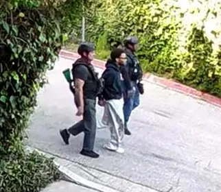 D4vd is handcuffed and escorted by two LAPD officers.