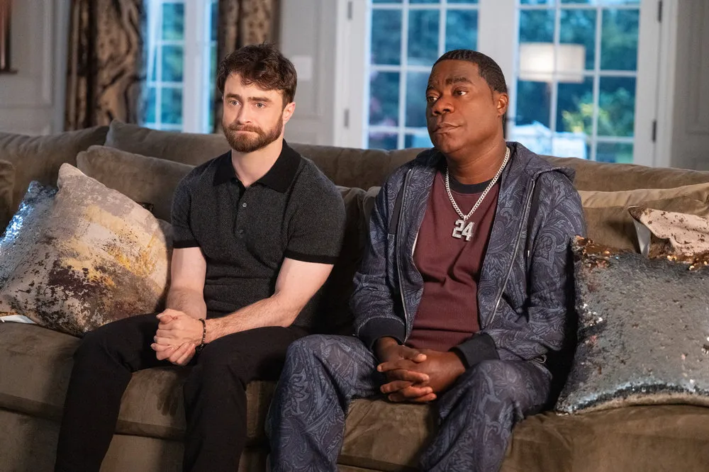 Daniel Radcliffe as Arthur Tobin and Tracy Morgan as Reggie Dinkins sitting on a couch.