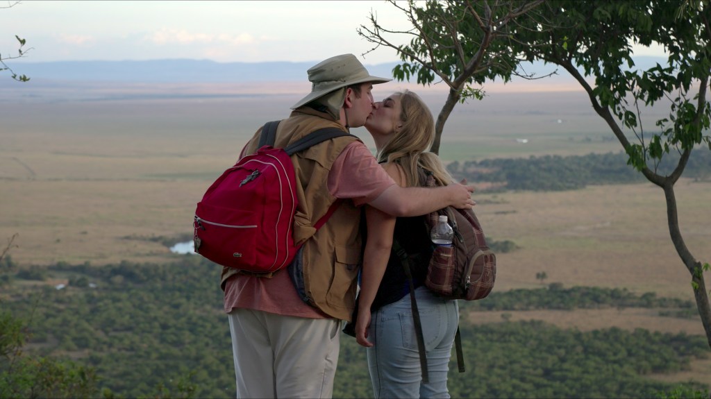 David and Abbey kiss with their arms around each other, overlooking a vast landscape.