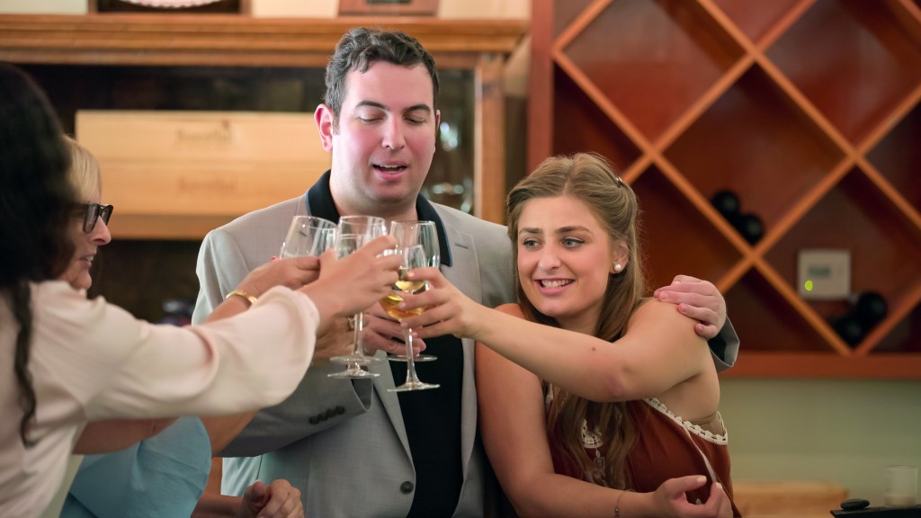 David and Abbey clink glasses with two other people.