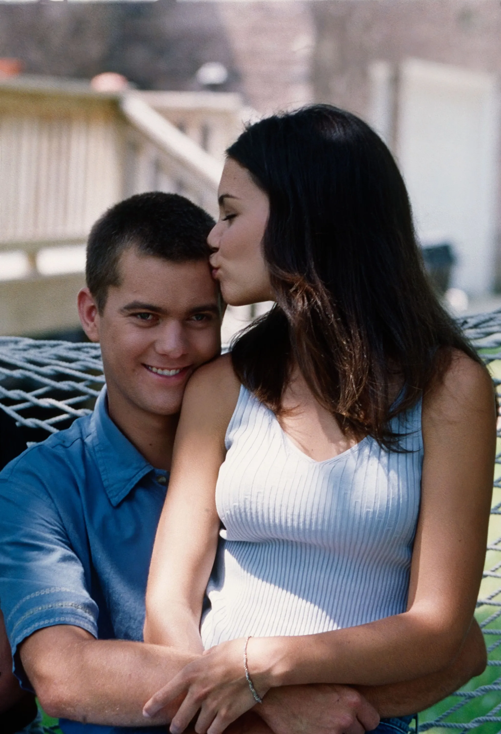 Joshua Jackson embracing and smiling at the camera as Katie Holmes kisses his forehead.
