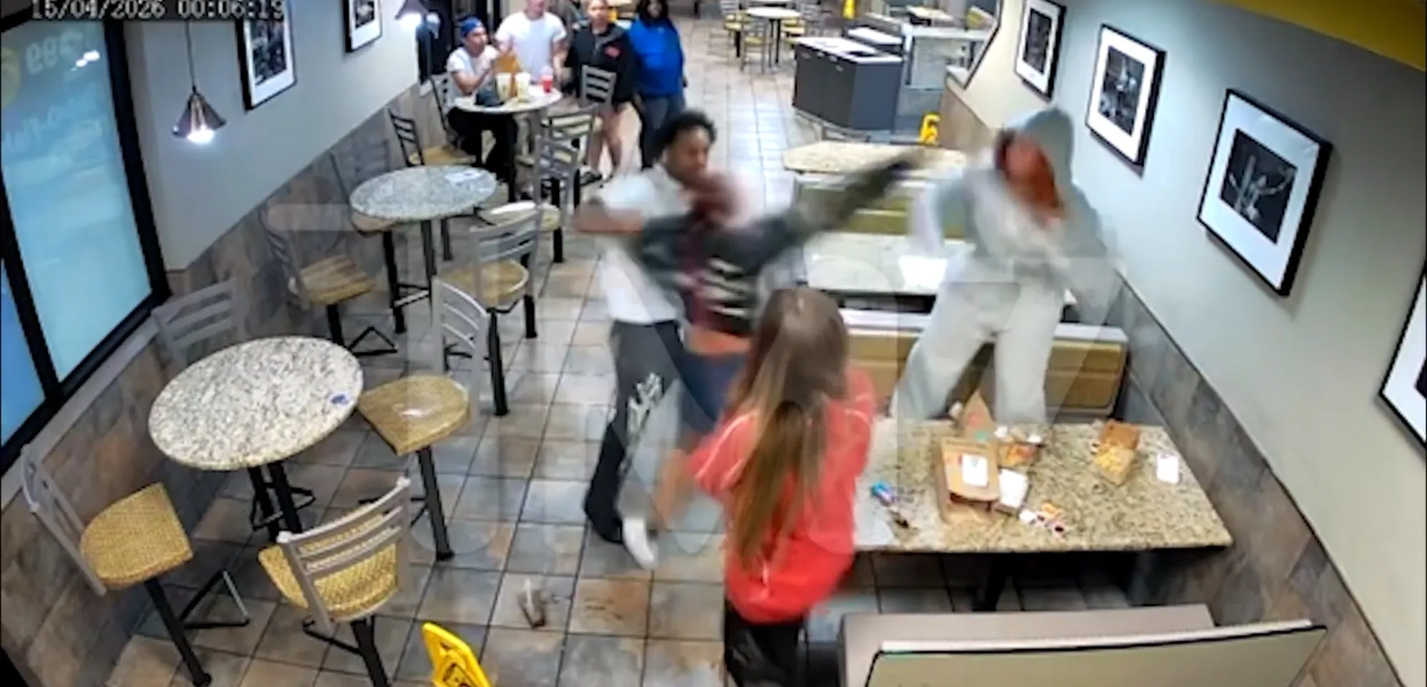 Security footage shows a fight inside a McDonald's, with one person on a table, another kicking, and a third on the floor.